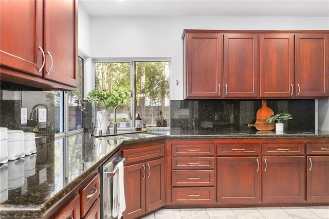 kitchen featuring sink, light tile patterned floors, dark stone countertops, tasteful backsplash, and stainless steel dishwasher