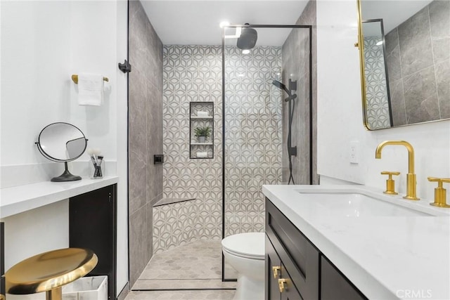 bathroom featuring vanity, a tile shower, and toilet