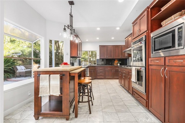 kitchen featuring pendant lighting, backsplash, stainless steel appliances, and a healthy amount of sunlight