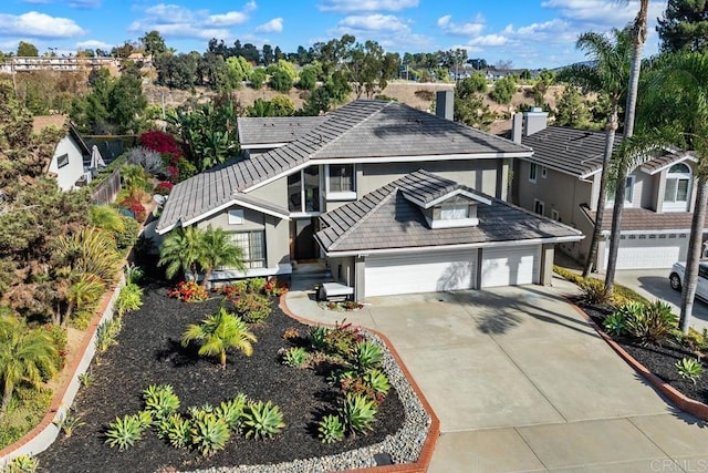 traditional-style house with a garage, concrete driveway, a tile roof, and stucco siding