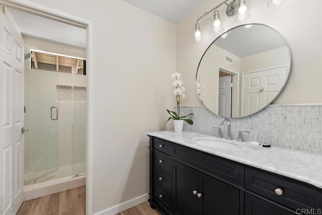 full bathroom featuring vanity, a shower stall, decorative backsplash, and wood finished floors