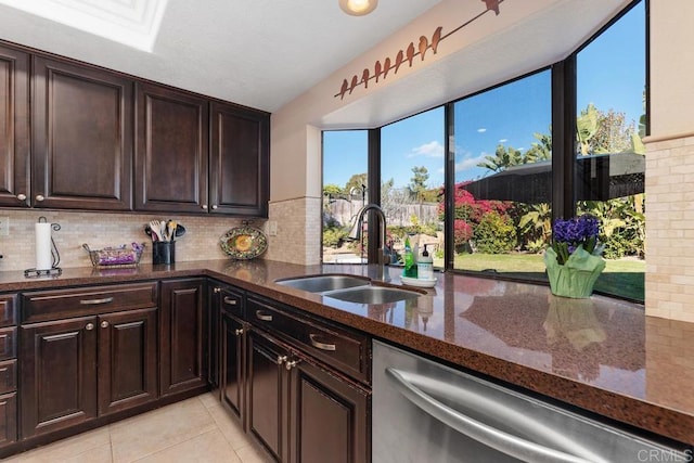 kitchen with dark stone countertops, a sink, dishwasher, and tasteful backsplash