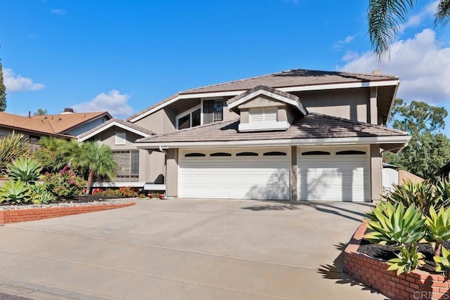 traditional-style home with driveway, an attached garage, and stucco siding