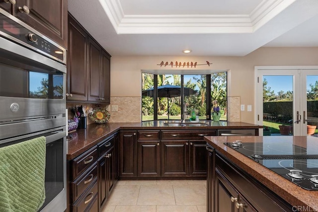 kitchen with dark countertops, double oven, black electric stovetop, and a sink