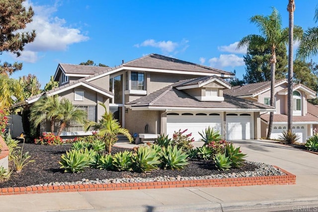 traditional-style house featuring a garage, driveway, and stucco siding