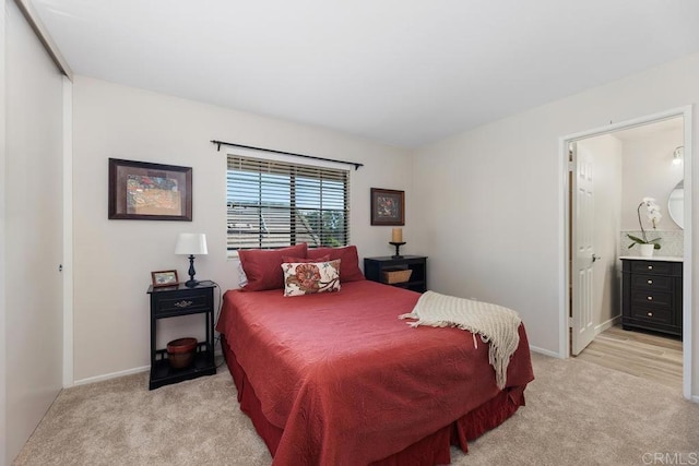 bedroom featuring light carpet, connected bathroom, and baseboards