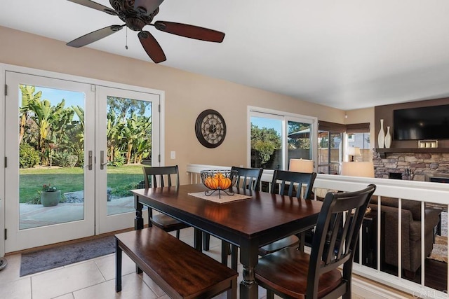 dining area featuring light tile patterned floors, a fireplace, and french doors