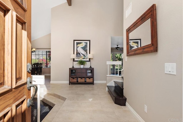 foyer entrance featuring high vaulted ceiling, light tile patterned flooring, visible vents, and baseboards