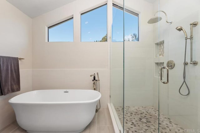 full bathroom featuring a stall shower and a soaking tub