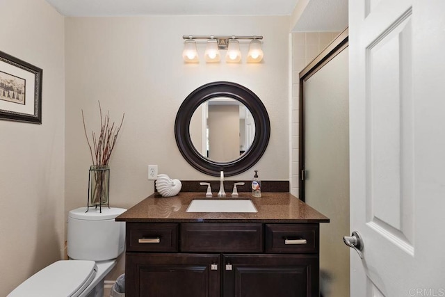 bathroom featuring toilet, a shower with door, and vanity