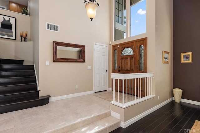 entrance foyer featuring visible vents, a towering ceiling, baseboards, and stairs