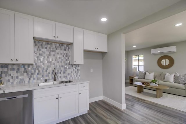 kitchen featuring sink, stainless steel dishwasher, a wall unit AC, and white cabinets