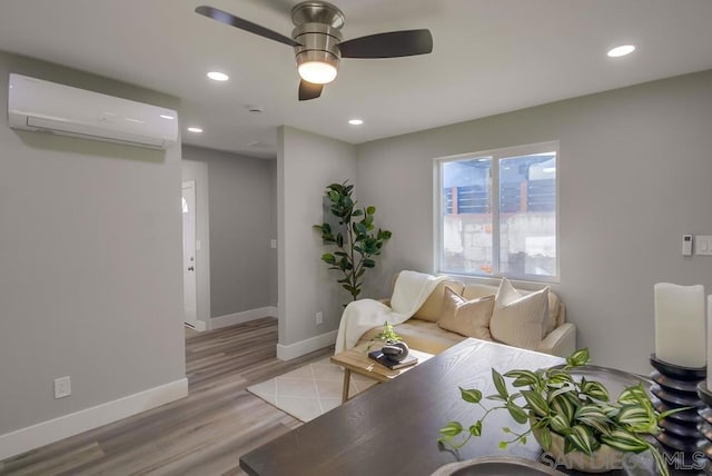 living room with light hardwood / wood-style floors, an AC wall unit, and ceiling fan