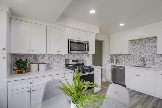 kitchen featuring sink, tasteful backsplash, white cabinetry, and appliances with stainless steel finishes