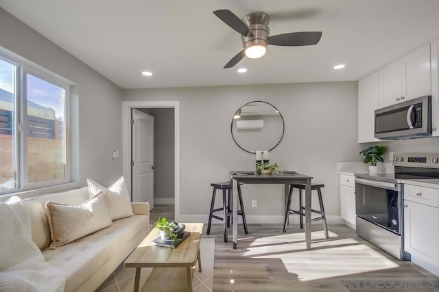 kitchen featuring white cabinetry, appliances with stainless steel finishes, light hardwood / wood-style flooring, and a wall mounted AC