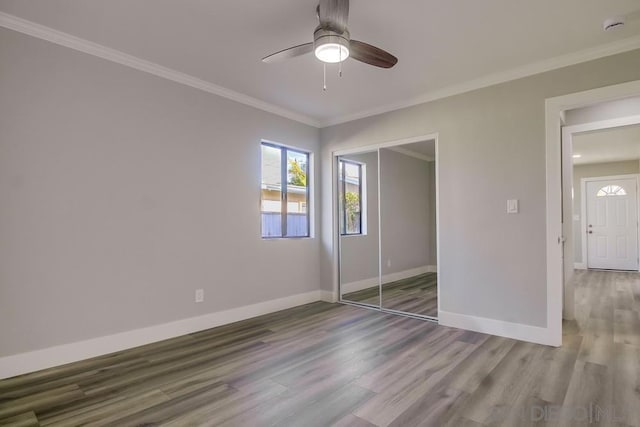 unfurnished bedroom with ceiling fan, hardwood / wood-style flooring, a closet, and ornamental molding