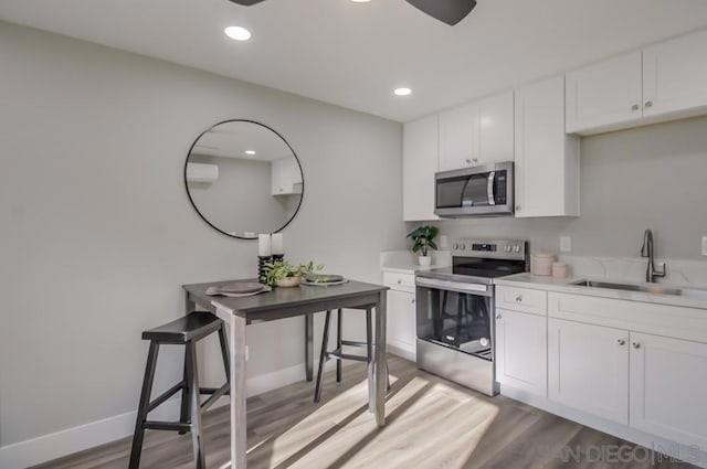 kitchen featuring sink, light hardwood / wood-style floors, white cabinetry, and appliances with stainless steel finishes