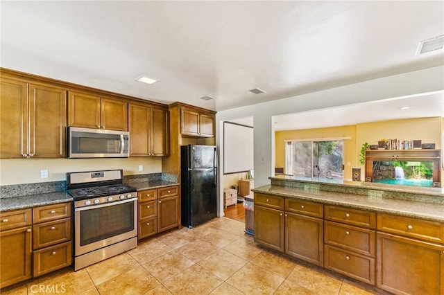 kitchen with light tile patterned floors, stainless steel appliances, and dark stone counters