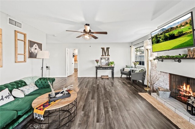 living room with a brick fireplace, dark hardwood / wood-style flooring, and ceiling fan