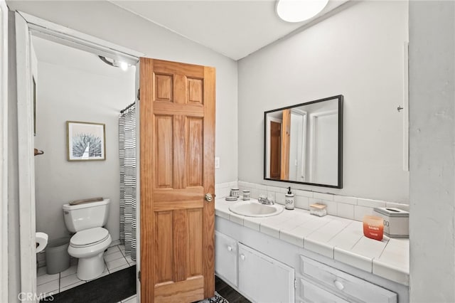 bathroom featuring vanity, vaulted ceiling, tile patterned floors, and toilet