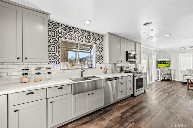 kitchen with sink, backsplash, gray cabinets, dark hardwood / wood-style floors, and stainless steel appliances