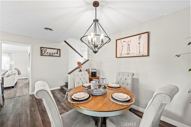 dining space featuring dark hardwood / wood-style floors and an inviting chandelier