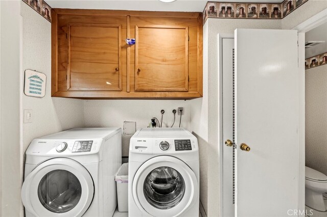 clothes washing area featuring cabinets and separate washer and dryer