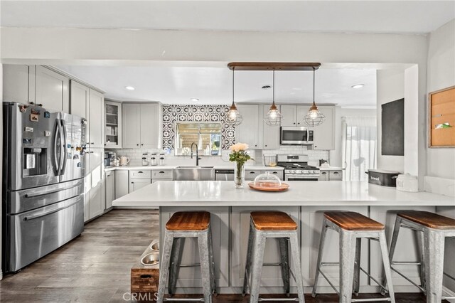 kitchen with sink, stainless steel appliances, pendant lighting, and tasteful backsplash