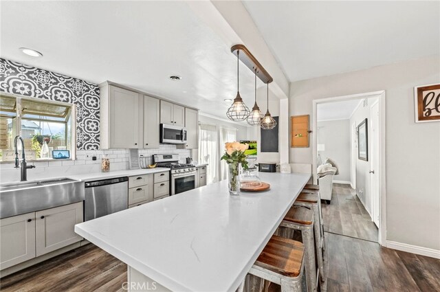 kitchen featuring appliances with stainless steel finishes, hanging light fixtures, sink, a breakfast bar, and a healthy amount of sunlight