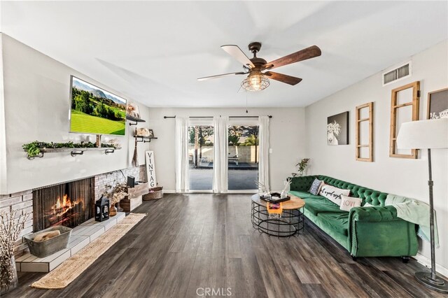 living room with a fireplace, dark wood-type flooring, and ceiling fan