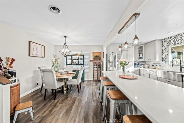 kitchen featuring decorative light fixtures, dark hardwood / wood-style flooring, tasteful backsplash, sink, and stainless steel fridge with ice dispenser