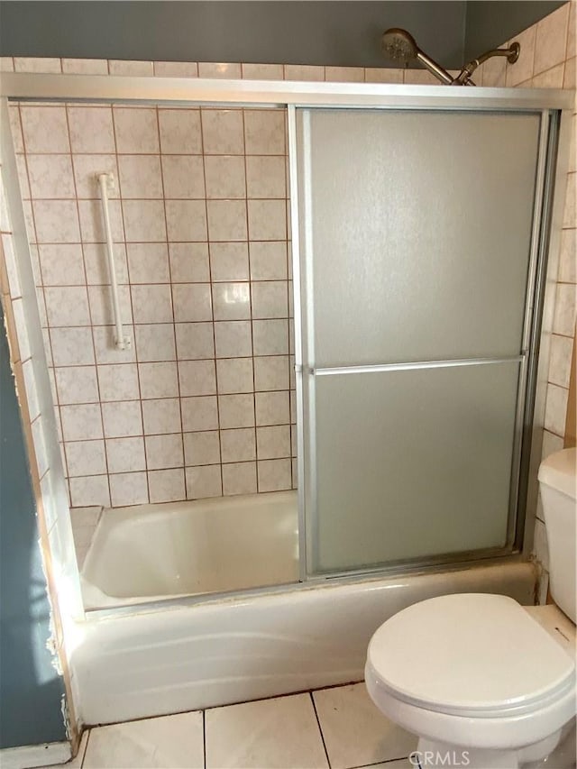 bathroom with combined bath / shower with glass door, toilet, and tile patterned flooring