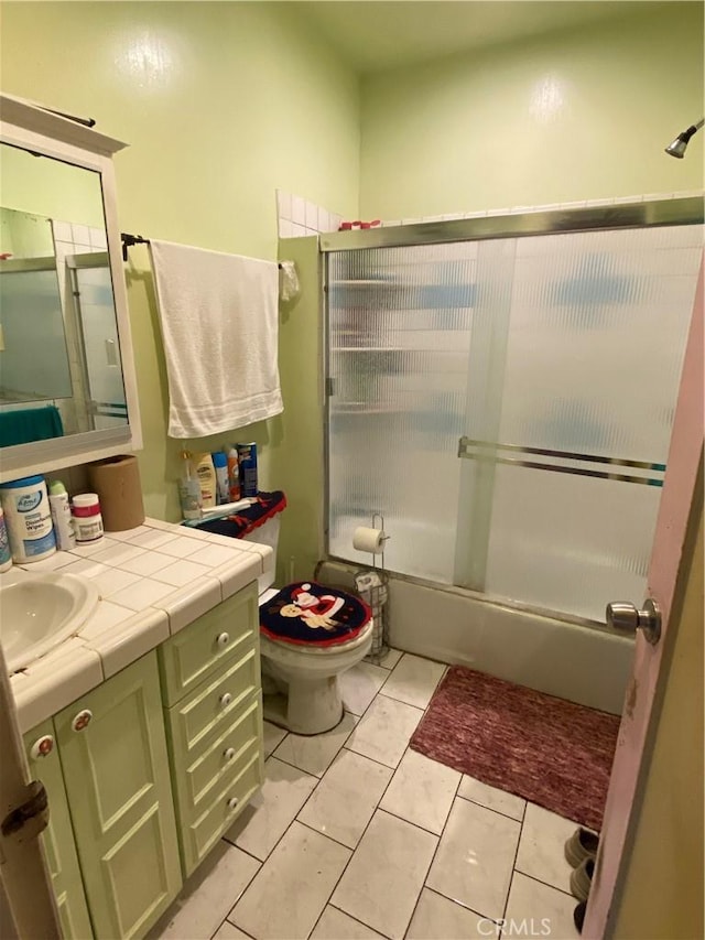 full bathroom featuring shower / bath combination with glass door, vanity, toilet, and tile patterned flooring