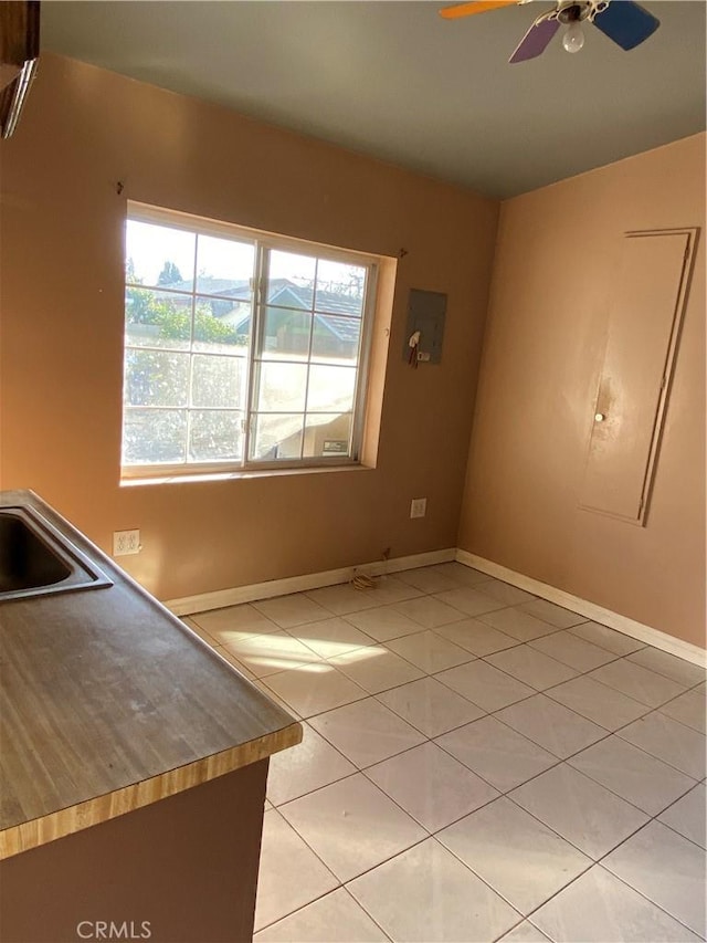 unfurnished living room with sink, light tile patterned floors, and ceiling fan