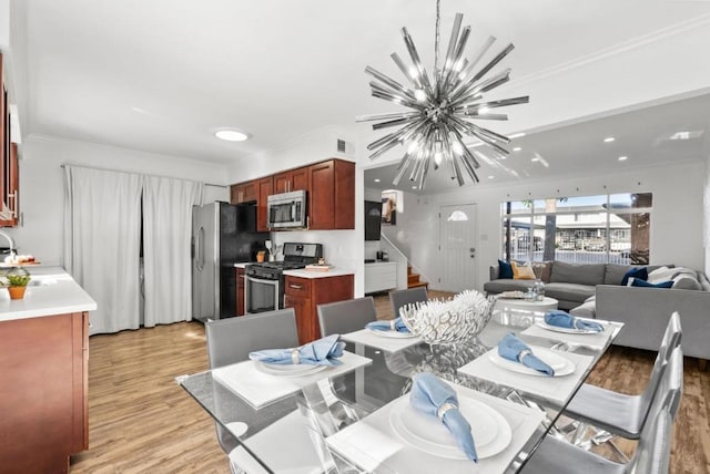 dining room featuring a notable chandelier, ornamental molding, light hardwood / wood-style floors, and sink