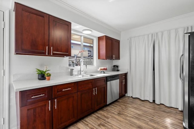 kitchen featuring ornamental molding, stainless steel appliances, light hardwood / wood-style floors, and sink