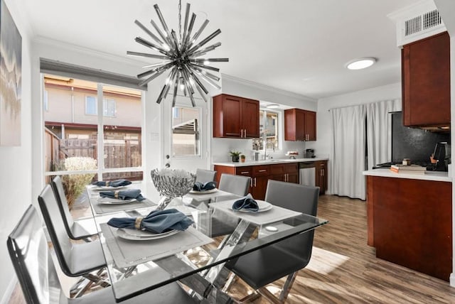 dining room with an inviting chandelier, hardwood / wood-style floors, crown molding, and sink