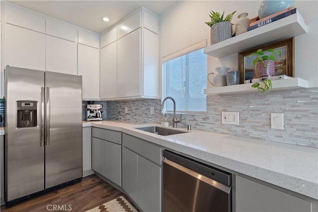 kitchen with dark wood-type flooring, stainless steel appliances, sink, backsplash, and light stone counters