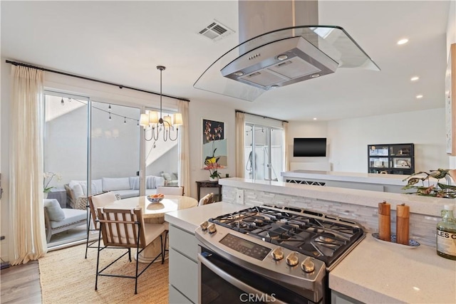 kitchen featuring white cabinets, stainless steel gas range oven, hanging light fixtures, a chandelier, and light wood-type flooring