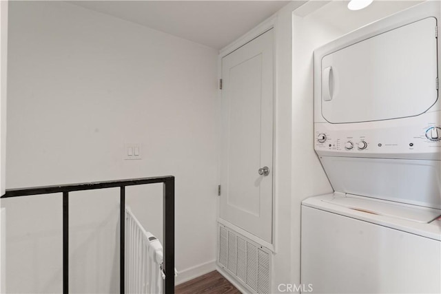 clothes washing area featuring dark wood-type flooring and stacked washer and clothes dryer