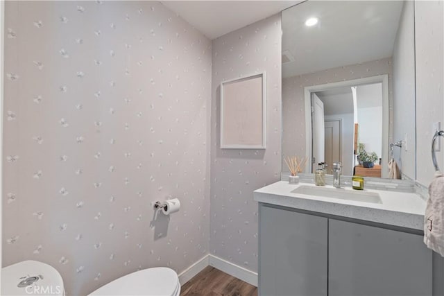 bathroom featuring wood-type flooring, toilet, and vanity