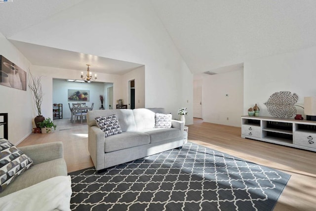 living room with wood-type flooring, a notable chandelier, and high vaulted ceiling