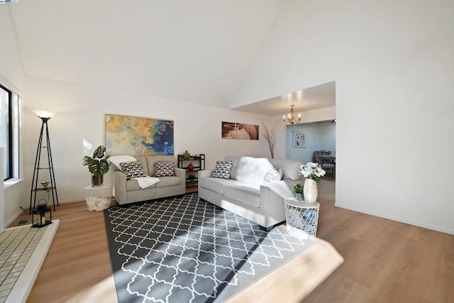 living room with a notable chandelier, hardwood / wood-style flooring, and high vaulted ceiling