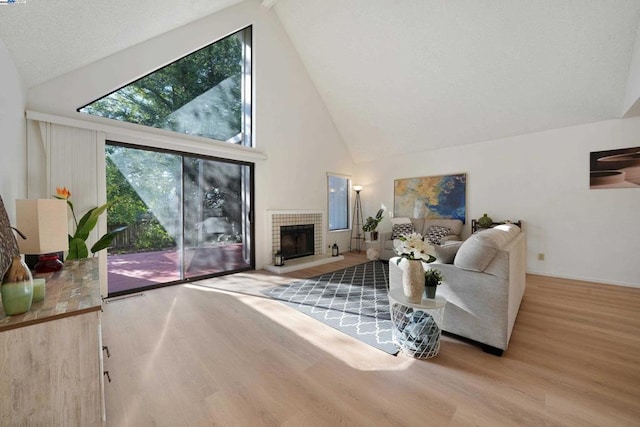 living room with a fireplace, high vaulted ceiling, and light wood-type flooring