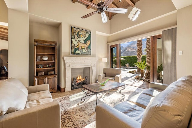 tiled living room with ceiling fan, a high ceiling, beam ceiling, and wooden ceiling