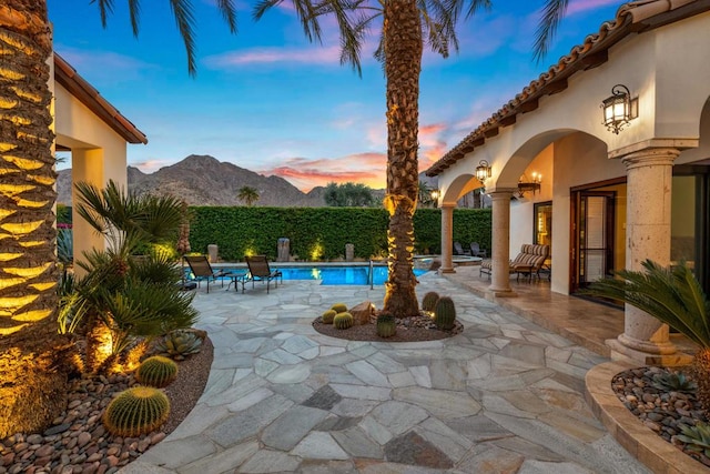 pool at dusk with a mountain view and a patio