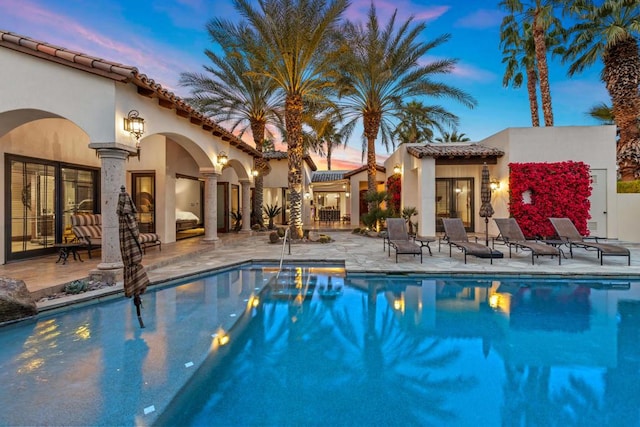 pool at dusk featuring a patio