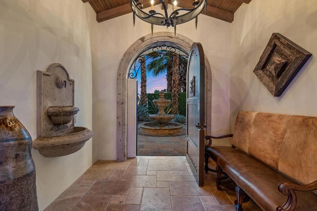 entryway featuring beam ceiling, wood ceiling, and an inviting chandelier