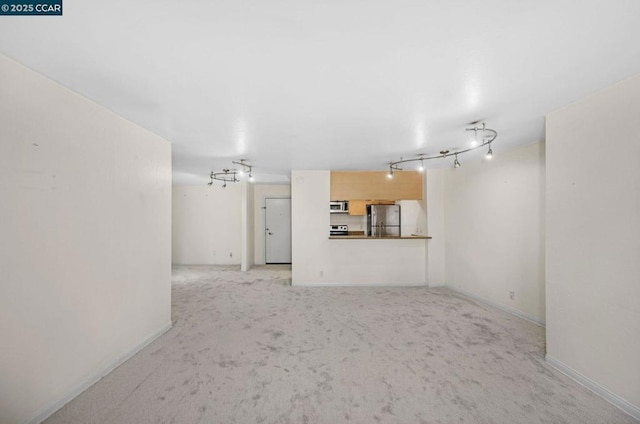 unfurnished living room featuring light colored carpet and track lighting