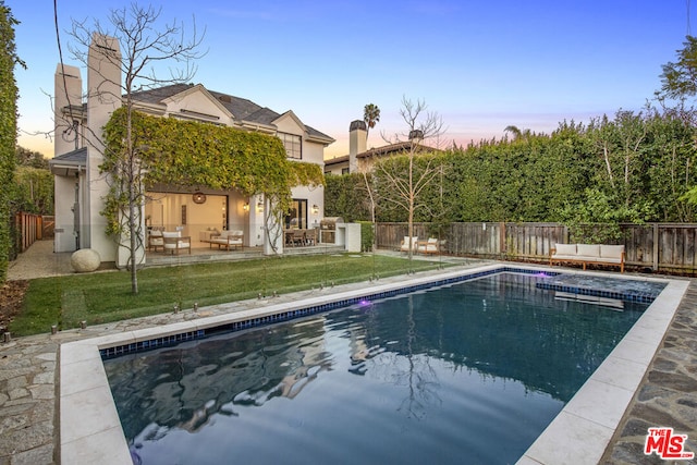 pool at dusk with a lawn and a patio